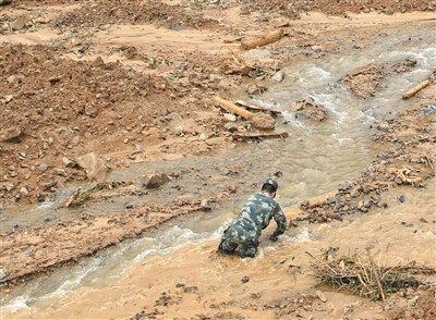 搜救现场一救援人员陷入淤泥。新京报记者 王嘉宁 摄